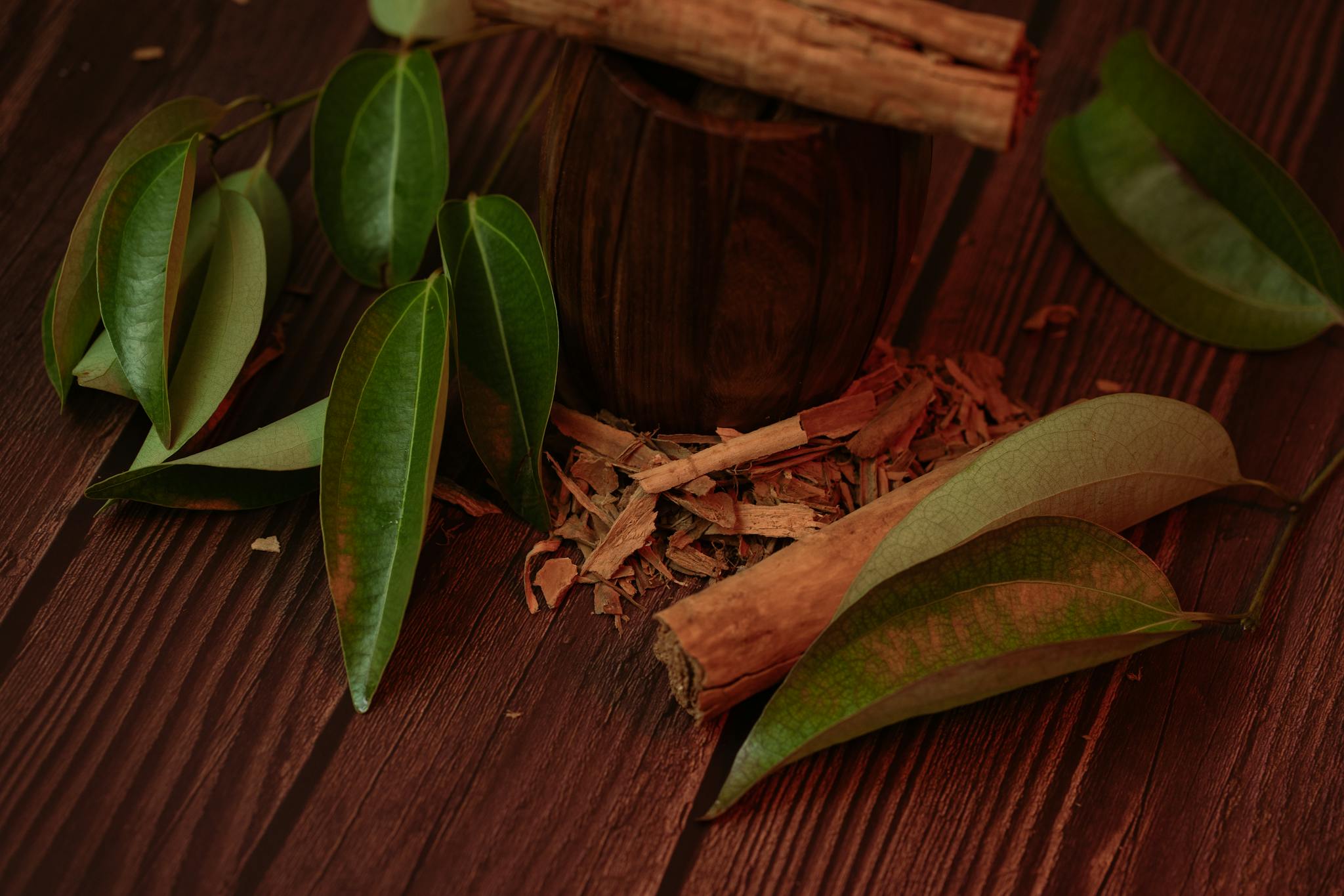 Cinnamon sticks and leaves on a wooden surface, highlighting their natural beauty.