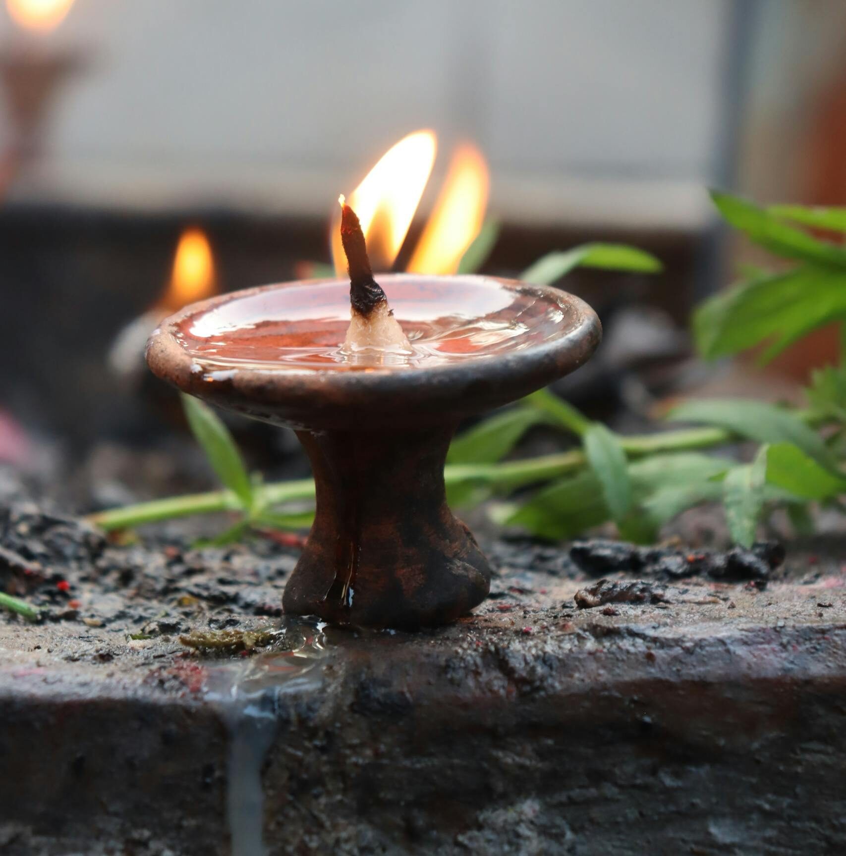 A close-up of a lit terracotta candle with natural surroundings, evoking warmth.