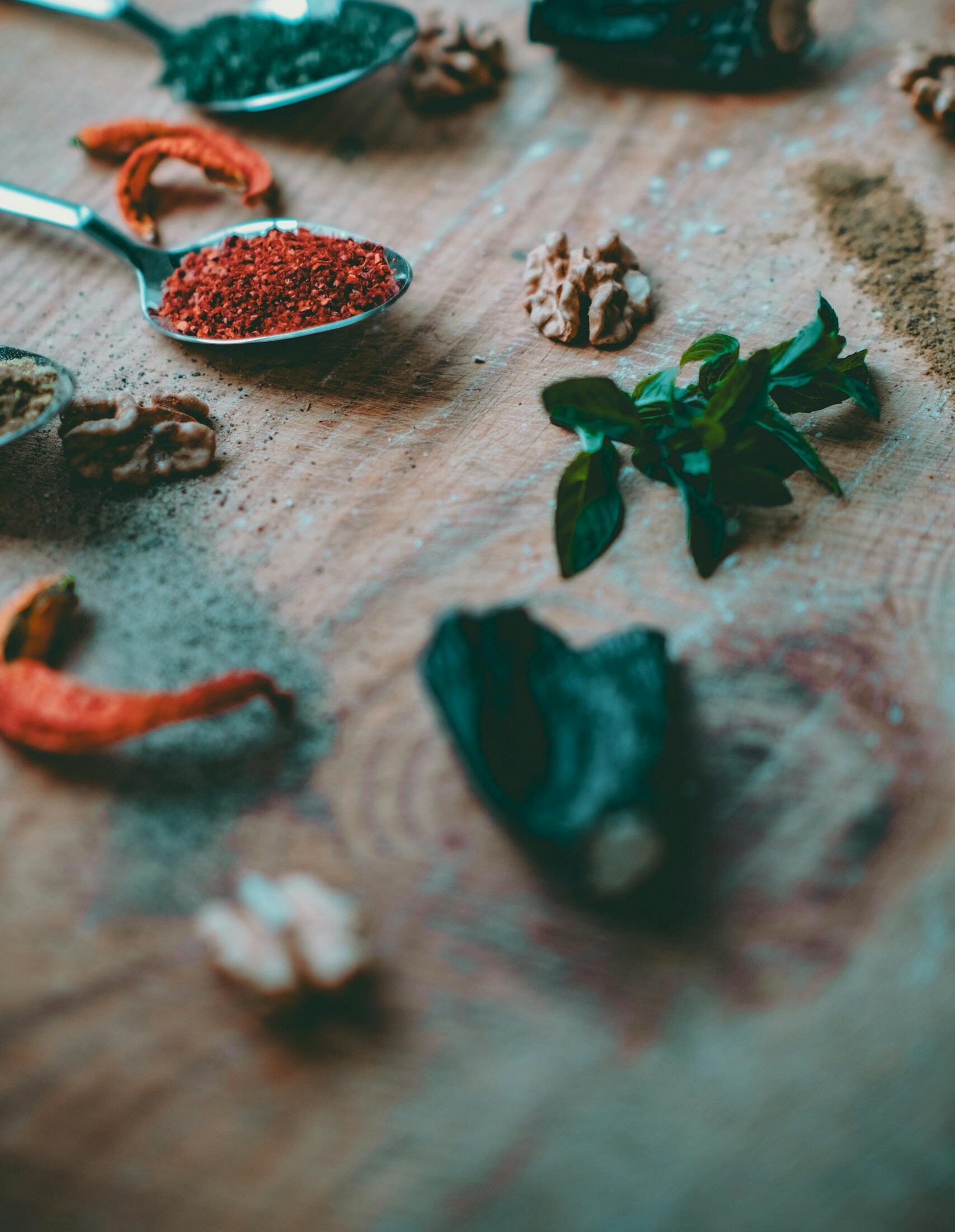 A selection of spices, herbs, and nuts on a wooden surface, perfect for culinary themes.